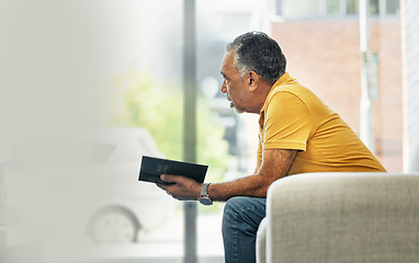 Image showing Senior man, reading and thinking with book on sofa in home living room learning knowledge, information or ideas. Elderly, person and relax in retirement with novel, books or fiction with mockup space