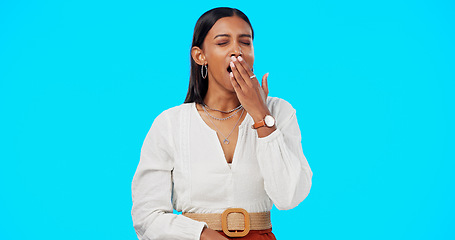 Image showing Woman, yawn and hand on mouth, tired and studio by blue background, alone or isolated. Overworked person, burnout and low energy for deadlines, exhausted and fatigue or lazy for nap, sleep and rest