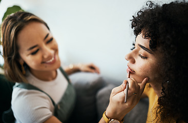 Image showing Friends, woman and relax with makeup in home with closeup for cosmetics, beauty and wellness. Young, people helping and apply lipstick with hand by holding, product and peace in happy with precision