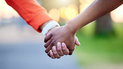 Image showing Interracial couple, holding hands and love in nature for support, trust or unity together. Closeup of people touching in romance, care or friendship walk in an outdoor park for partnership or duo