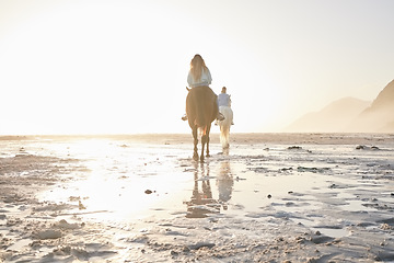 Image showing Woman, horse riding and friends on beach with sand for travel, vacation or holiday trip outdoor in nature. Back, people and animal in summer with lens flare by ocean or sea for sunset and travelling