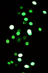 Image showing Green light, bokeh and shine on black background isolated on a mockup space. Blur, dark backdrop and defocused glow, sparkle or glitter at night for Christmas, holiday or party with magic color dots