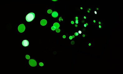 Image showing Green light, bokeh and shine on dark background on a mockup space. Blur, black backdrop and defocused dots, sparkle or glitter glow at night for Christmas, holiday or party with magic color wallpaper