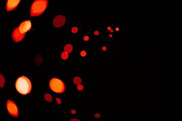 Image showing Red, lights and bokeh in a studio with dark background for celebration, event or party. Confetti, glitter and color sparkles for magic, shine or glow for festive by black backdrop with mockup.