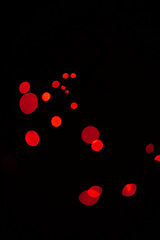 Image showing Bokeh, red dots and lights on black background with pattern, texture and mockup with cosmic aesthetic. Night lighting, sparkle particles and glow on dark wallpaper with space, color shine and flare.