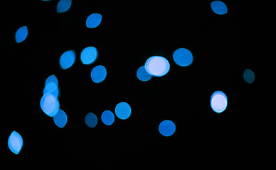 Image showing Blue, glitter and bokeh in a studio with dark background for celebration, event or party. Confetti, lights and color sparkles for magic, shine or glow for festive by black backdrop with mockup.