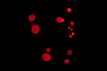 Image showing Bokeh, red particles and lights on black background with pattern, texture and mockup with cosmic aesthetic. Night lighting, sparkle dots and glow on dark wallpaper with space, color shine and flare.