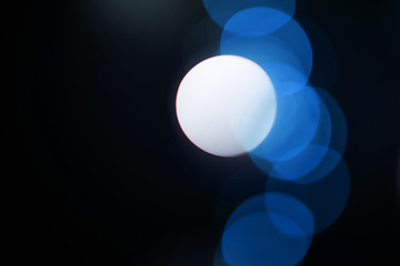 Image showing Bokeh, blue particles and neon on black background with pattern, texture and mockup with cosmic aesthetic. Night lighting, sparkle lights and glow on dark wallpaper with space, color shine and flare.