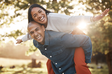 Image showing Couple, park and happy with piggy back, portrait and airplane game in nature, holiday and bonding in summer. Man, woman and playful in backyard, freedom and vacation by trees with love in sunshine