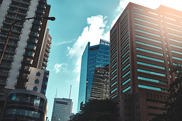 Image showing City, buildings and infrastructure with landscape for urban skyscraper or architecture outdoor with clouds. Development, town and skyline with cityscape, tower and hotel with modern exterior or roof