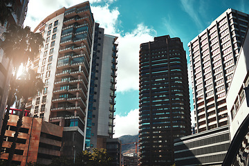 Image showing City, buildings and development with landscape for urban infrastructure or architecture outdoor. Skyscraper, town and skyline with cityscape, tower and hotel facade with modern exterior and sky