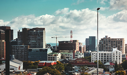 Image showing City, buildings and skyscraper with landscape for urban infrastructure or architecture outdoor in nature. Development, town and skyline with cityscape, tower and hotel for modern exterior and clouds