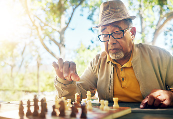 Image showing Playing, chess and senior man outdoor with game of strategy and thinking in retirement for mental challenge. Boardgame, choice and elderly person in park, woods or nature and move piece in checkmate