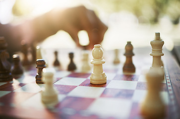 Image showing Closeup, chess and hand at park for challenge, strategy and moving silhouette in sunshine. Person, vintage board game and outdoor for contest, battle and problem solving with competition in summer