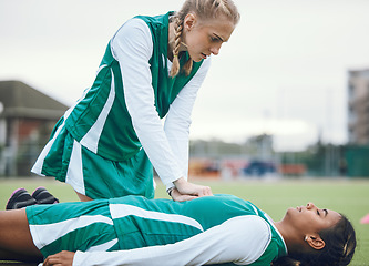 Image showing First aid, cpr and accident with a hockey player on a field to save a player on her team during an emergency. Fitness, sports and heart attack with a woman helping her friend on a field of grass