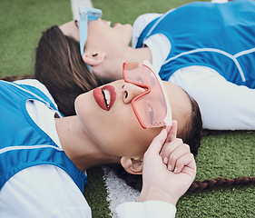 Image showing Style, sports and women hockey players relaxing on the grass field with cool, stylish and trendy outfit. Fashion, fitness and portrait of female athlete friends laying in stadium after game or match.