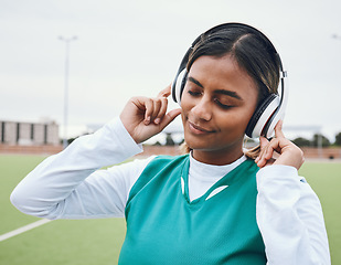 Image showing Athlete, sports or woman in headphones for music or streaming radio playlist on a hockey turf. Relax, break or zen Indian girl player listening to calm audio, sound or fitness podcast for inspiration