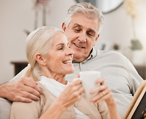 Image showing Senior couple, coffee and reading book on a sofa with love, smile and retirement in a home. Elderly people, communication and lounge on a couch with study for knowledge in a house happy and relax
