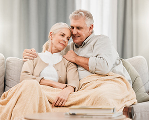 Image showing Senior couple, bonding and care on a living room sofa with hug and relax at home. Elderly people, bonding and marriage love in retirement with blanket and calm in a lounge on a couch together