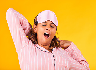 Image showing Wake up, yawn and a woman on a yellow background in pyjamas for sleeping, tired and in the morning. Fatigue, young and a girl or person in clothes for rest, comfort and a nap in a studio for night