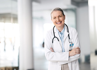 Image showing Doctor, woman and happy with arms crossed in hospital, standing and smile for medicine. Mature, person and healthcare for research, treatment or surgery with specialist in cardiology with stethoscope