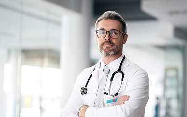 Image showing Serious doctor, portrait and man with arms crossed in hospital for healthcare, wellness or career. Face, medical professional and confident surgeon, expert and mature employee in glasses in Canada