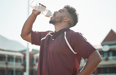 Image showing Football player, drink water and rest on sports field for training completion, workout and exercise outdoors. Fitness, workout and male athlete with liquid bottle for wellness, hydration or practice