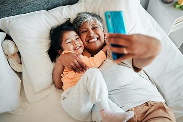 Image showing Selfie, smile and grandmother with child on bed bonding, relax and love for happy family with care. Photography, technology and senior woman with little girl in bedroom on video call together in home