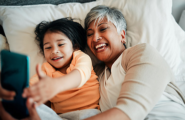 Image showing Selfie, smile and old woman with child on bed bonding, relax and love for happy family with care. Photography, technology and grandmother with little girl in bedroom on video call together in home