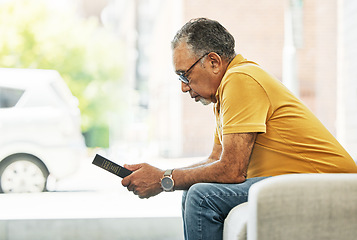 Image showing Serious, mature man and reading bible in home, praying and thinking in living room on sofa. Person, holy book and gospel in house for learning religion, studying and Christian worship in retirement