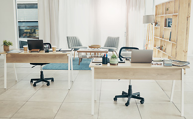 Image showing Empty office, interior and coworking space with laptop on desk in startup company. Computer, table and creative workplace room with wood furniture, chair and modern design in workspace for business