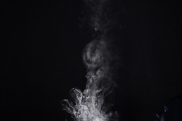 Image showing Smoke, vapor or gas in a studio with dark background by mockup space for magic effect with abstract. Incense, steam or fog mist moving in air for cloud smog pattern by black backdrop with mock up.
