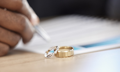 Image showing Divorce, rings and signature on paperwork for a lawyer, register wedding or writing on a contract. Table, closeup and a certificate, planning or legal documrnts for a commitment or engagement