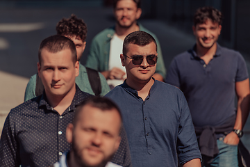 Image showing A diverse group of businessmen and colleagues walking together by their workplace, showcasing collaboration and teamwork in the company.