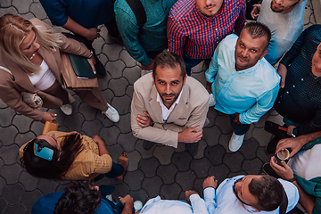 Image showing A top view photo of group of businessmen and colleagues standing together, looking towards the camera, symbolizing unity and teamwork.