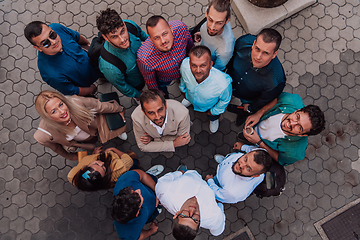 Image showing A top view photo of group of businessmen and colleagues standing together, looking towards the camera, symbolizing unity and teamwork.