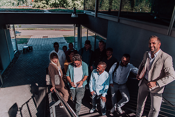 Image showing A diverse group of businessmen and colleagues walking together by their workplace, showcasing collaboration and teamwork in the company.