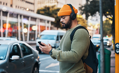 Image showing Phone, headphones of student and man in city listen to music, sound or audio. Smartphone, radio and serious person in street for streaming podcast, typing on social media and reading email to travel