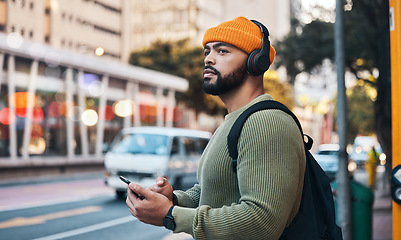 Image showing Phone, headphones of student and thinking in city, listening to music or sound . Smartphone, radio and serious man in street for streaming podcast, typing on social media and reading email to travel