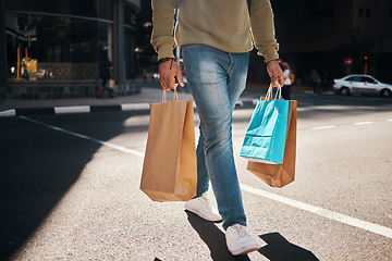 Image showing Man, legs and shopping bags in street of city, pedestrian or crosswalk for travel, shop or mall. Male person or shopper walking on road with paper bag for discount, sale or retail store in urban town