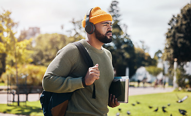 Image showing Man on campus, walking with books and headphones on morning commute for education with backpack. Learning, studying and college student in park listening to podcast, music or streaming online lecture