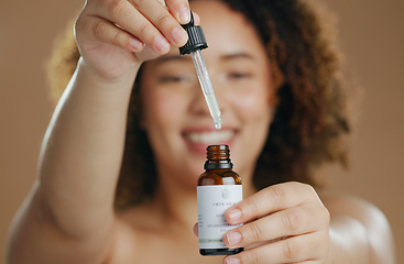 Image showing Skincare, beauty or hands of woman with serum in studio for a natural glow, wellness or cosmetic routine. Bottle closeup, product or model with facial oil in dermatology treatment on brown background