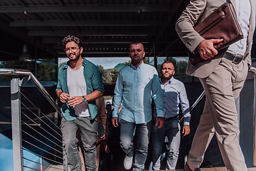 Image showing A diverse group of businessmen and colleagues walking together by their workplace, showcasing collaboration and teamwork in the company.