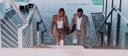 Image showing Modern business couple after a long day's work, walking together towards the comfort of their home, embodying the perfect blend of professional success and personal contentment.