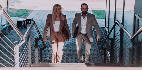 Image showing Modern business couple after a long day's work, walking together towards the comfort of their home, embodying the perfect blend of professional success and personal contentment.