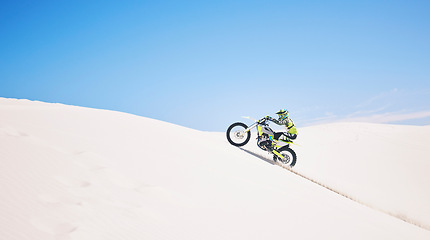 Image showing Man, driving and motorbike on sand with blue sky or sport, adventure and outdoor race in summer or mockup space. Motorcycle, ride and athlete on off road, dirt or desert for challenge and danger