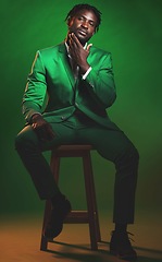 Image showing Fashion, formal and portrait of a black man in a suit sitting on a chair in studio with a luxury outfit. Elegant, stylish and African male model with fashionable clothes isolated by green background.