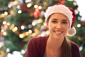 Image showing Christmas, woman and happy holiday portrait with cheerful smile at festive tree in home. Christmas tree, happiness and excited girl in home for vacation celebration with red santa hat.