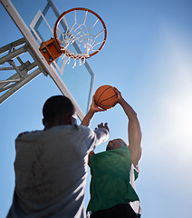 Image showing Basketball player, low angle and competition games on blue sky background of outdoor sports, fitness and energy for goals, performance and action. Basketball hoop, friends and men, court and training