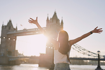 Image showing Woman, freedom and travel by the London bridge or city for holiday break or outdoor summer vacation. Joyful female tourist with open arms enjoying sunny adventure trip, traveling and sightseeing